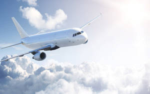 White Airplane Soaring Above Majestic Clouds Wallpaper