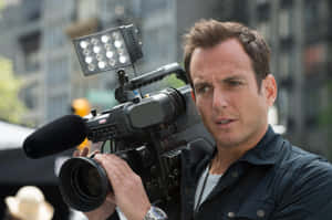 Will Arnett Striking A Casual Pose Against A Blue Background Wallpaper