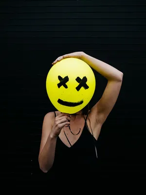 Woman Holding A Yellow Smiley Face Balloon Wallpaper