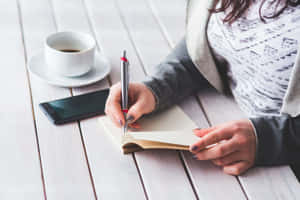 Woman Writingin Notebookat Cafe Wallpaper