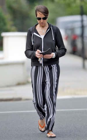 Womanin Casual Attire Walkingand Checking Phone Wallpaper