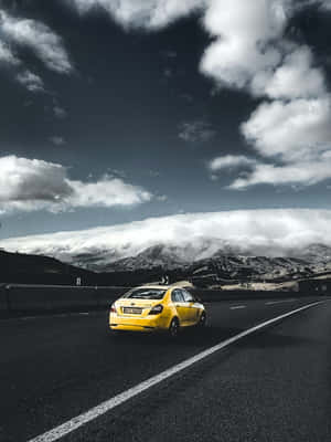 Yellow Car Mountainous Roadscape Wallpaper