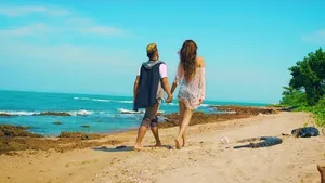 Young Couple Holding Hands On A Sunlit Beach Wallpaper