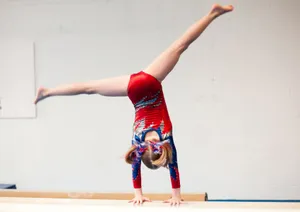 Young Gymnast Performs Cartwheel On Balance Beam Wallpaper