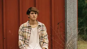 Young Man Against Red Barn Wall Wallpaper