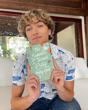 Young Man Holding Book The Summer I Turned Pretty Wallpaper