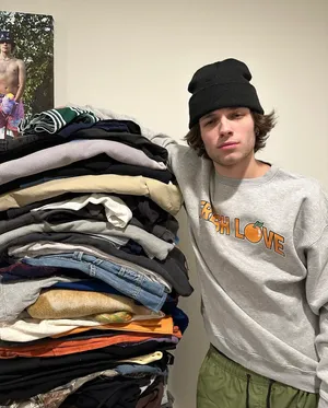 Young Man Leaningon Clothes Pile Wallpaper