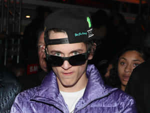 Young Manin Purple Jacketand Black Cap Wallpaper