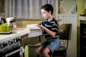 Young Sheldon Readingat Kitchen Counter Wallpaper