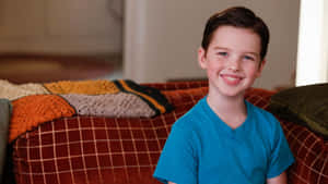 Young Sheldon Smiling Couch Scene Wallpaper