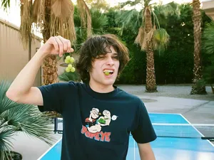 Youth Eating Grapes Outdoors Wallpaper